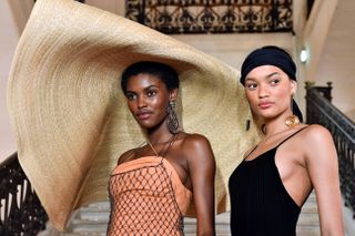A model wears Jacquemus's oversize straw hat next to a model not wearing a hat