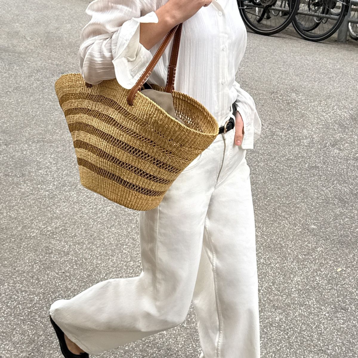 An image of @claradyrhauge wearing white jeans, one of the biggest summer jeans trends of 2026, with a basket bag and white shirt. 