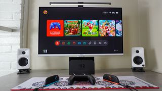 A desk setup built around the Nintendo Switch 2 with the Switch 2 Pro Controller and the Joy-Con 2 controllers on a mouse mat