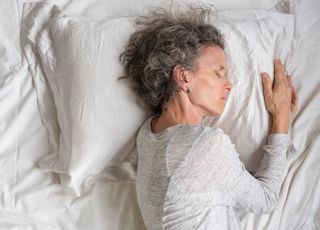 a woman with grey frizzy hair sleeping on a silk pillow