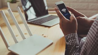 A photograph of a man connecting his smartphone to a Wi-Fi router