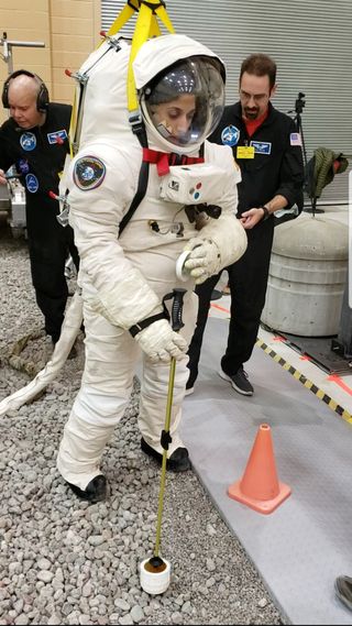 Shawna Pandya (in the spacesuit) completes a test with a soil sampling tool.