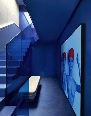 A royal blue stairwell with a blue artwork featuring two barbie dolls