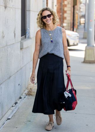 A woman in New York wearing a sleeveless grey top with a long black skirt.