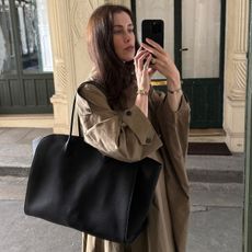 Woman wears trench coat and carries black bag