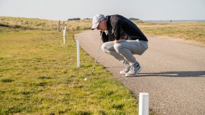 A golfer checking if his ball is out of bounds or not