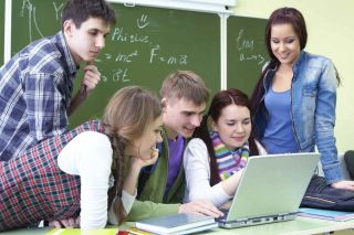 Teens looking at laptop computer in math class