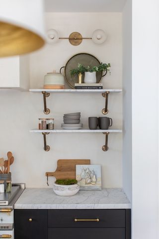 kitchen open shelving in marble styled with crockery, plant and books