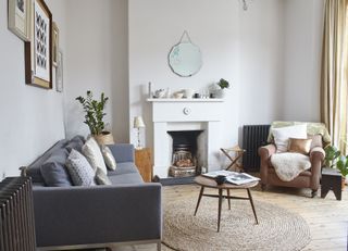 Living room with round jute rug, grey sofa, white fireplace and chandelier with blue glass hangings