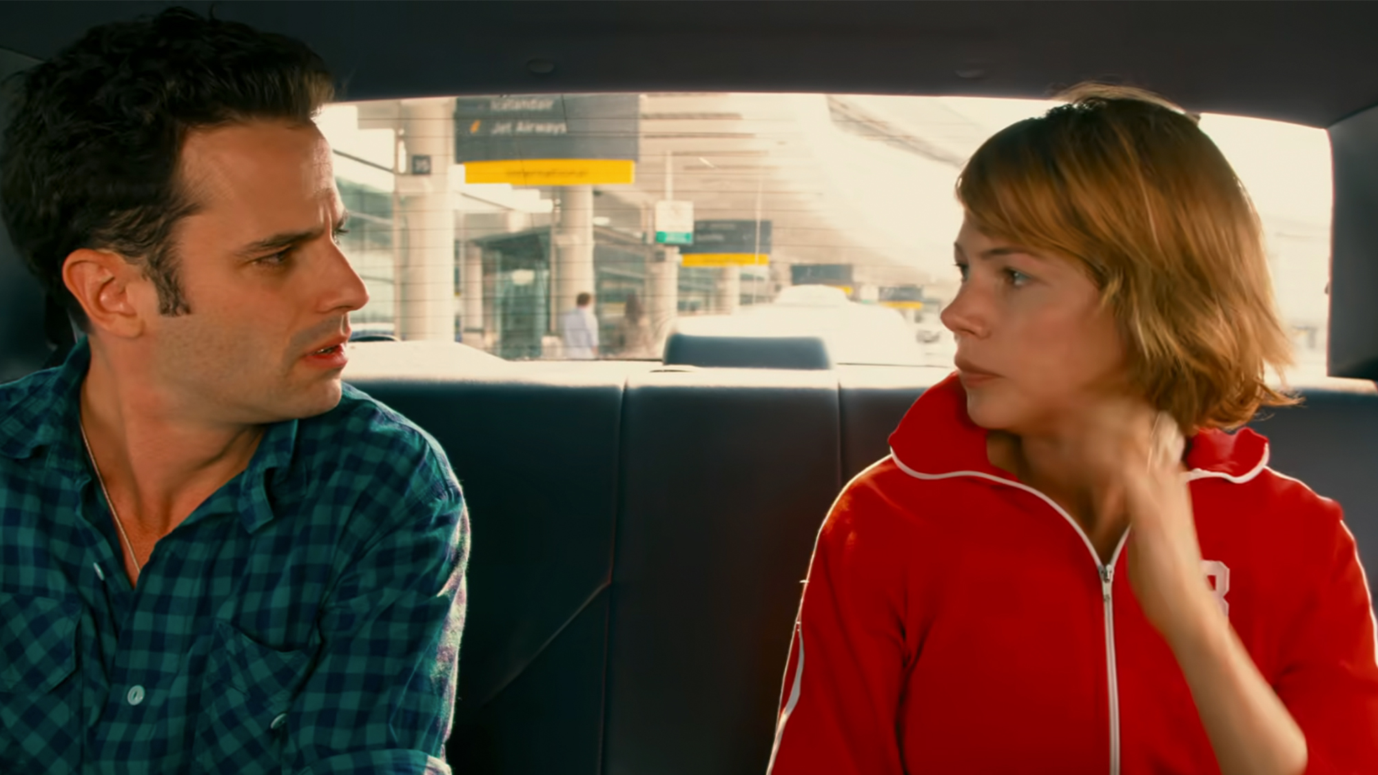 Two people talking in the back of a car.