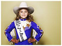 Image of a blond haired girl with cowboy hat, blue costume and sash