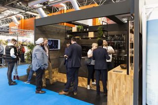 A kitchen stall at one of the Homebuilding & Renovating Shows with multiple people crowding round and asking questions to representatives
