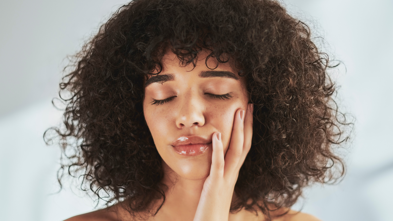 Face, beauty and skincare with a black woman in studio to promote natural cosmetics or treatment. Facial, skin and wellness with an attractive young female touching her cheek after natural care