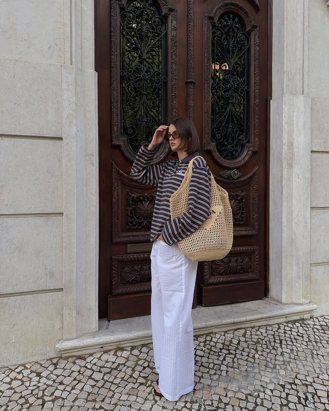 @maryljean wears a striped polo, linen trousers, raffia bag and sandals