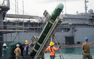 Submariners and Military Sealift Command civilian mariners secure an MK-48 torpedo to a crane as they onload to the USS Topeka on June 7.