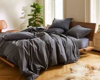 Classic Core Sheet Set in graphite color in bedroom with big plant, wooden bed frame and white fluffy rug