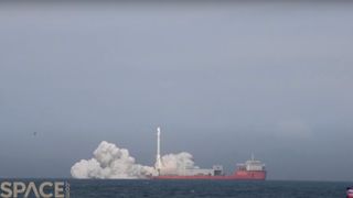 a white rocket launches from a red ship at sea into a blue sky.