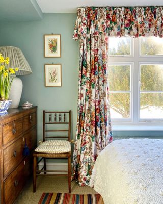 green bedroom with floral curtains and valance with antique furniture