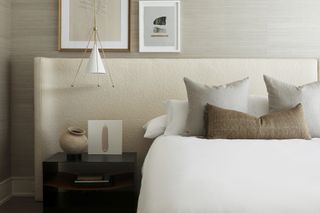 neutral bedroom with boucle headboard, pendant light, artwork, black side table, vase, pillows