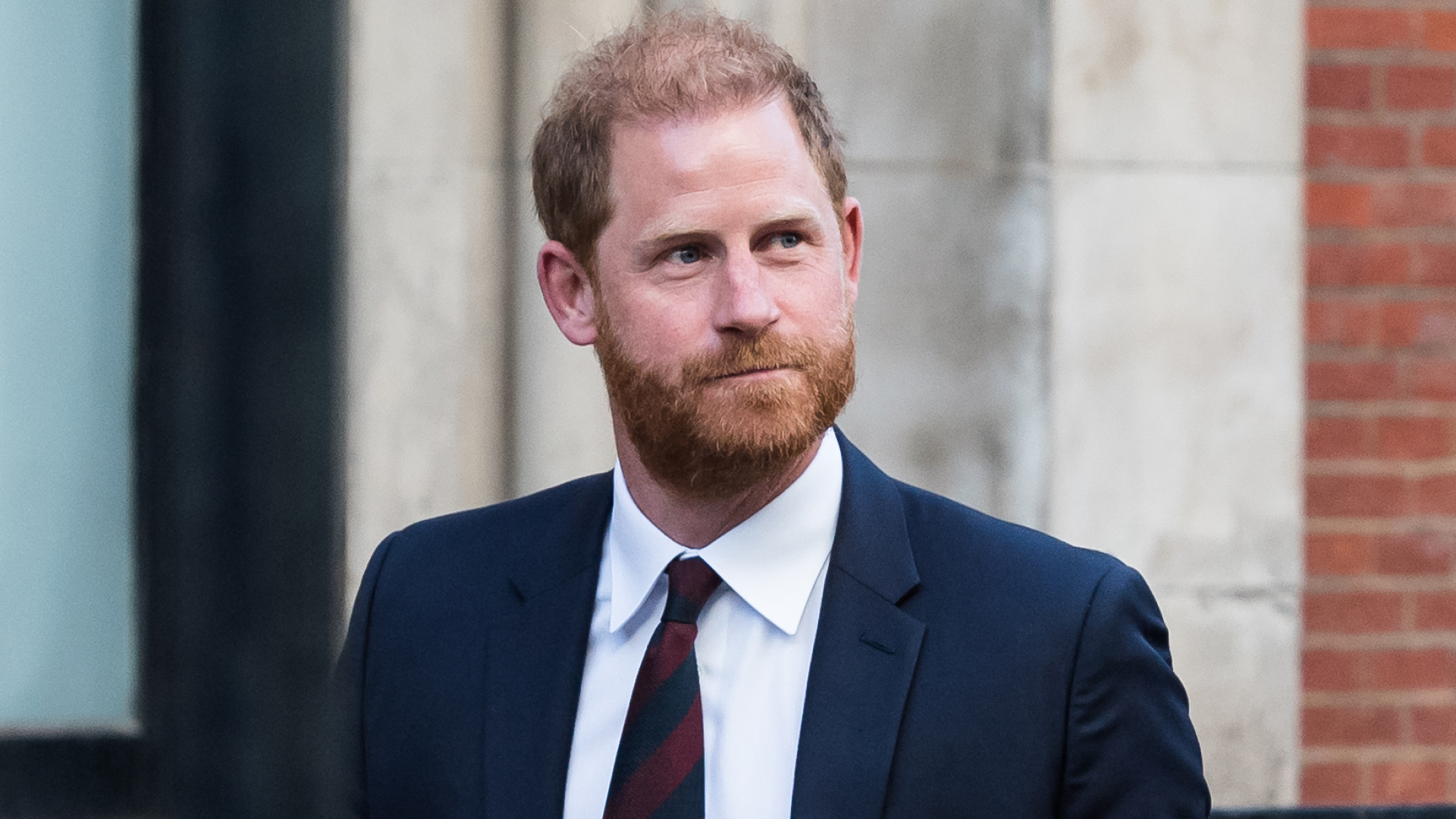 Prince Harry wearing a blue suit and red and blue striped tie