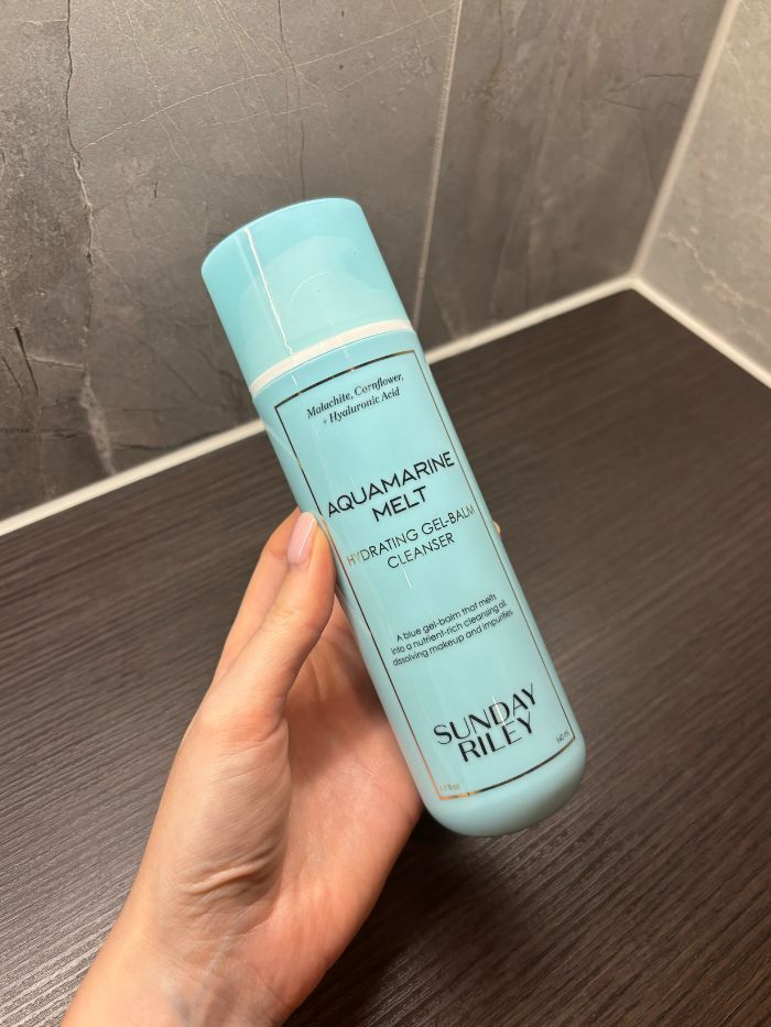 Deputy beauty editor Grace Lindsay holding the Sunday Riley Aquamarine Melt Cleansing Gel-Balm