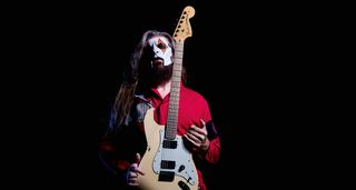 A portrait of a masked Jim Root with his signature white Charvel S-style