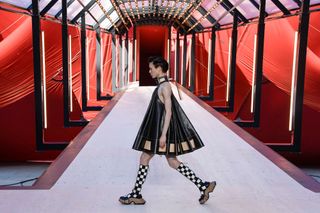 A model walking on the runway at Louis Vuitton show with red backdrop
