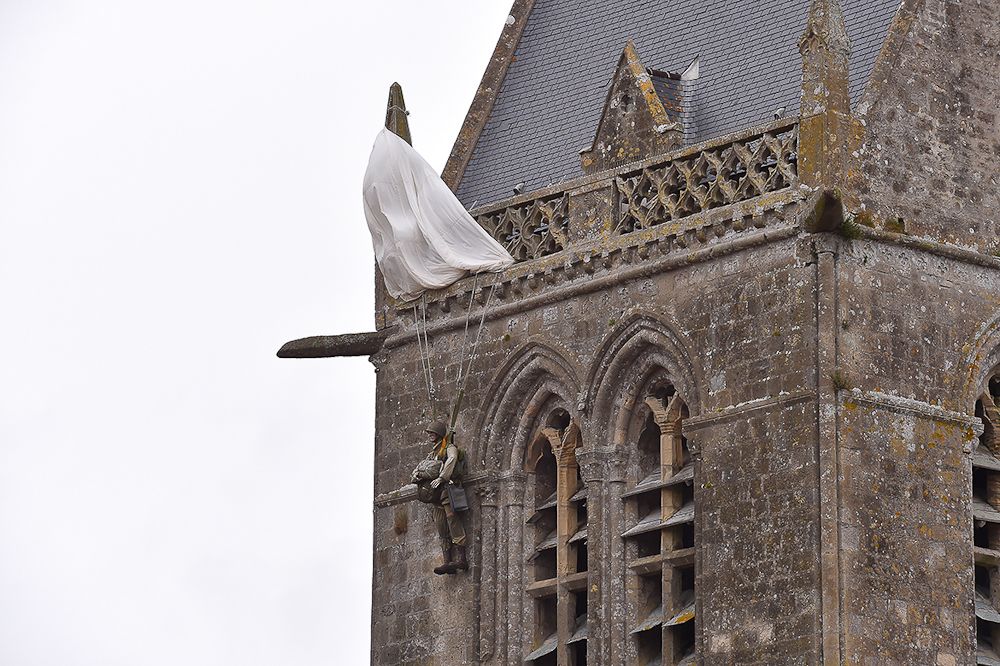 A replica of a WWII paratrooper hangs from a steeple near the team presentation