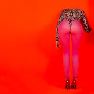 St Vincent's Masseduction album cover shows a woman in leopard print leotard, pink tights and heels from behind, leaning forwards towards a red background