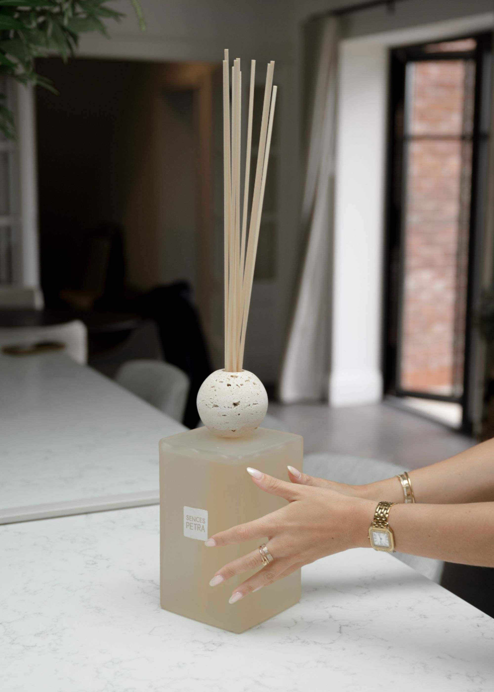 A giant reed diffuser on top of a kitchen counter with a woman&#039;s hand around it