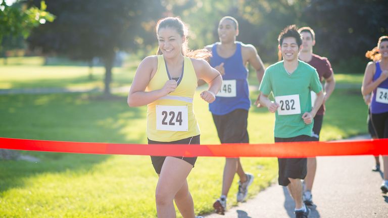 Woman crossing the finish line in a race, after working to improve 5k time