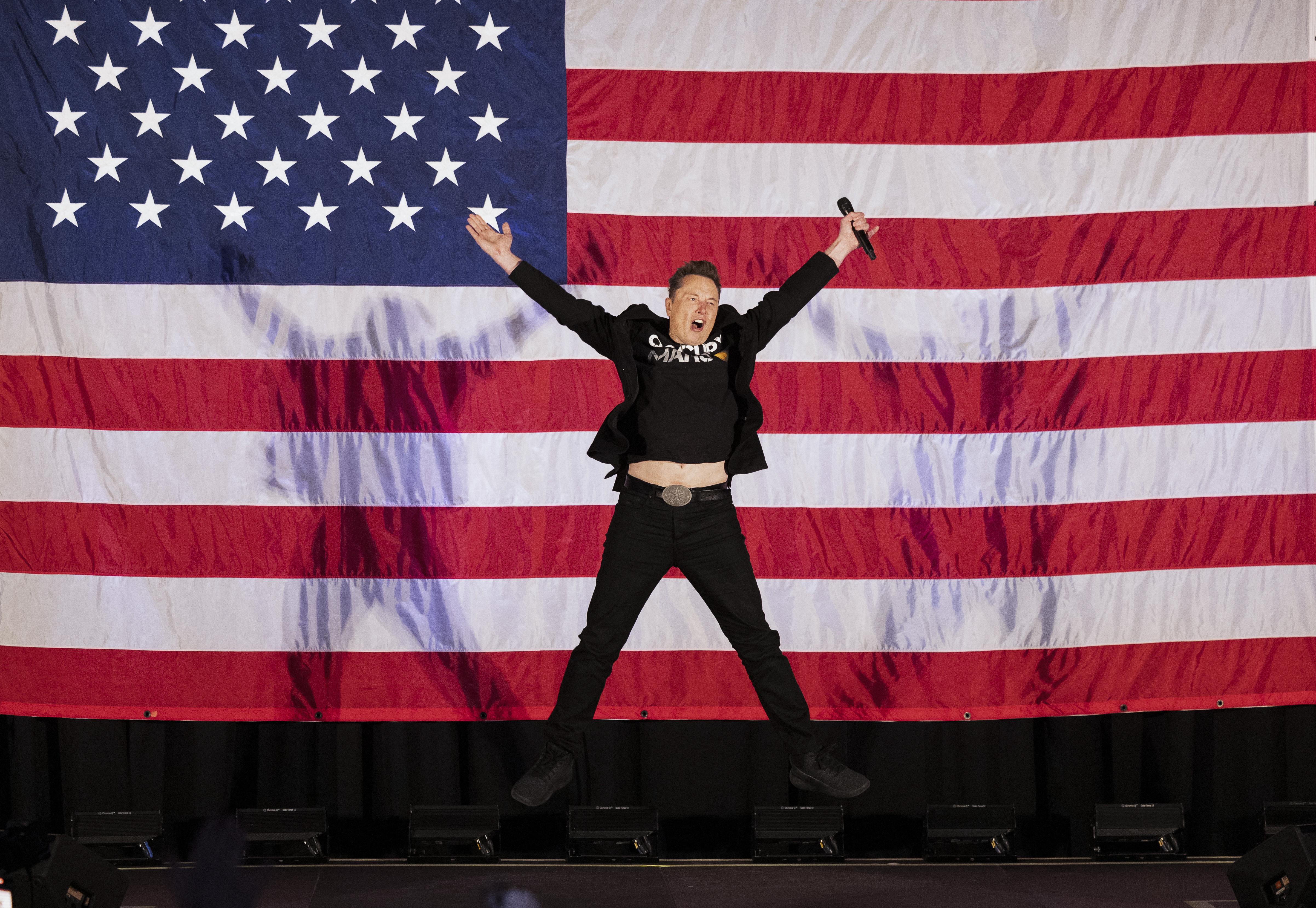Tesla and SpaceX CEO Elon Musk jumps on stage as he arrives to speak at a town hall event hosted by America PAC in support of former US President and Republican presidential candidate Donald Trump at the Greater Philadelphia Expo Center in Oaks, Pennsylvania, on October 18, 2024. Musk is holding several events in the key swing-state of Pennsylvania in support of former US President and Republican presidential candidate Donald Trump. 