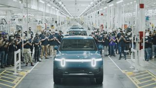 Electric truck rolling off a production line in a factory surrounded by workers