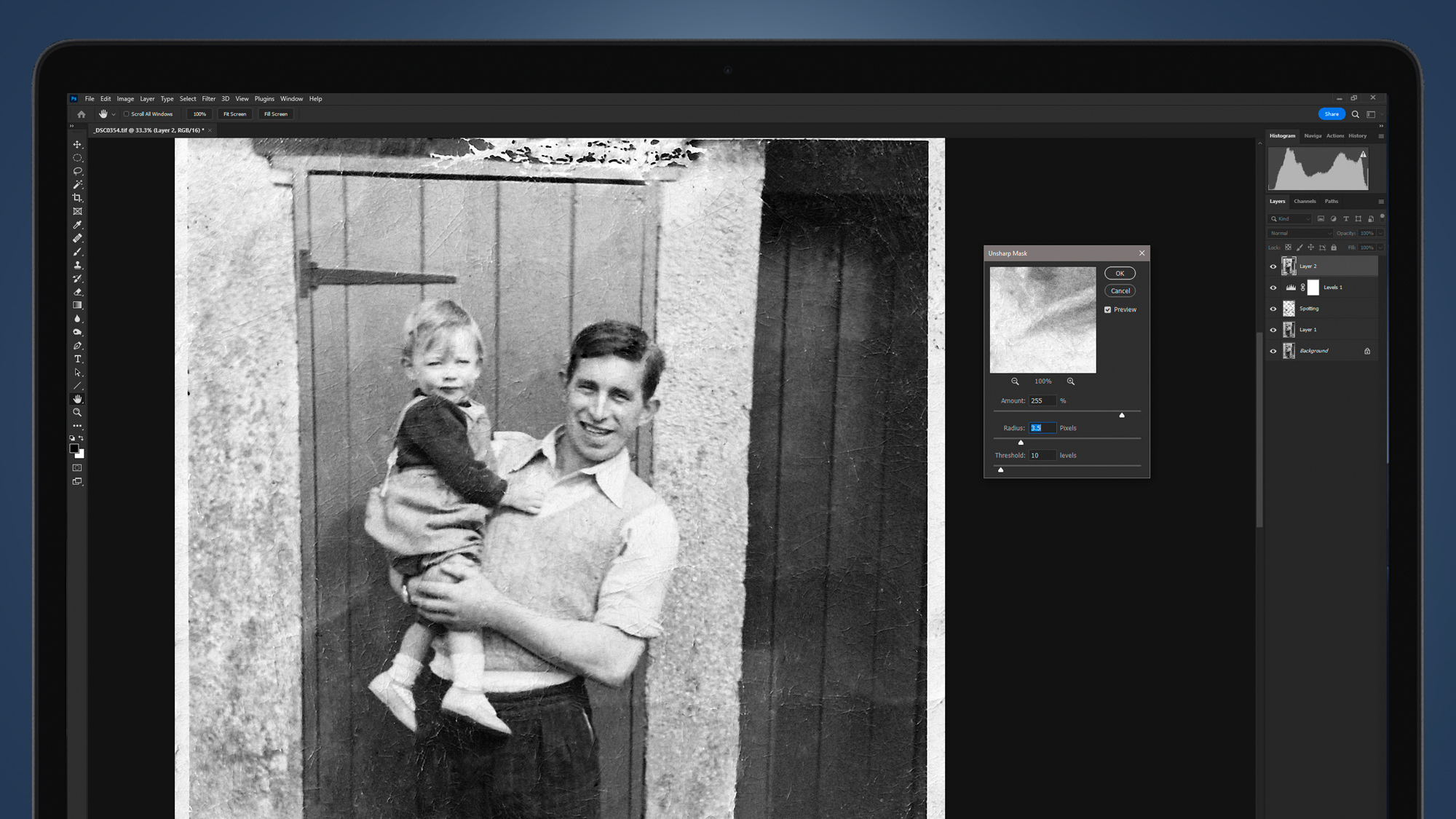 A laptop screen with an old photo restored in Photoshop