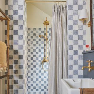 small shower room with chequerboard grey and white tiles in enclosure and brass fittings