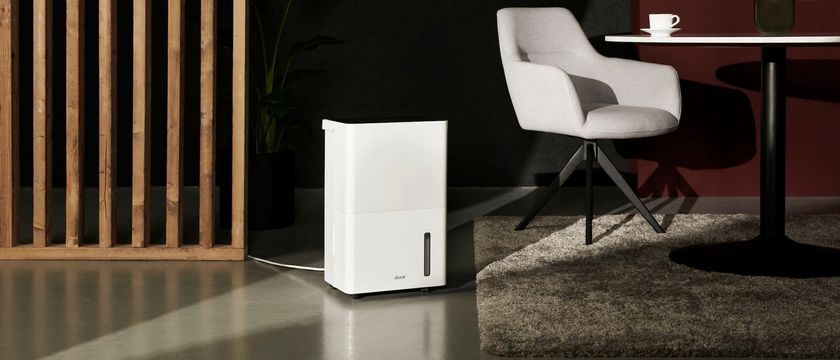A Duux 20L dehumidifier next to a white chair