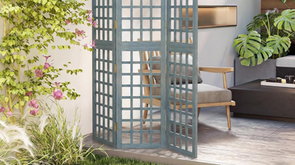OUTSUNNY's foldable privacy screen on a patio with a chair next to it in a corner seating area with foliage all around