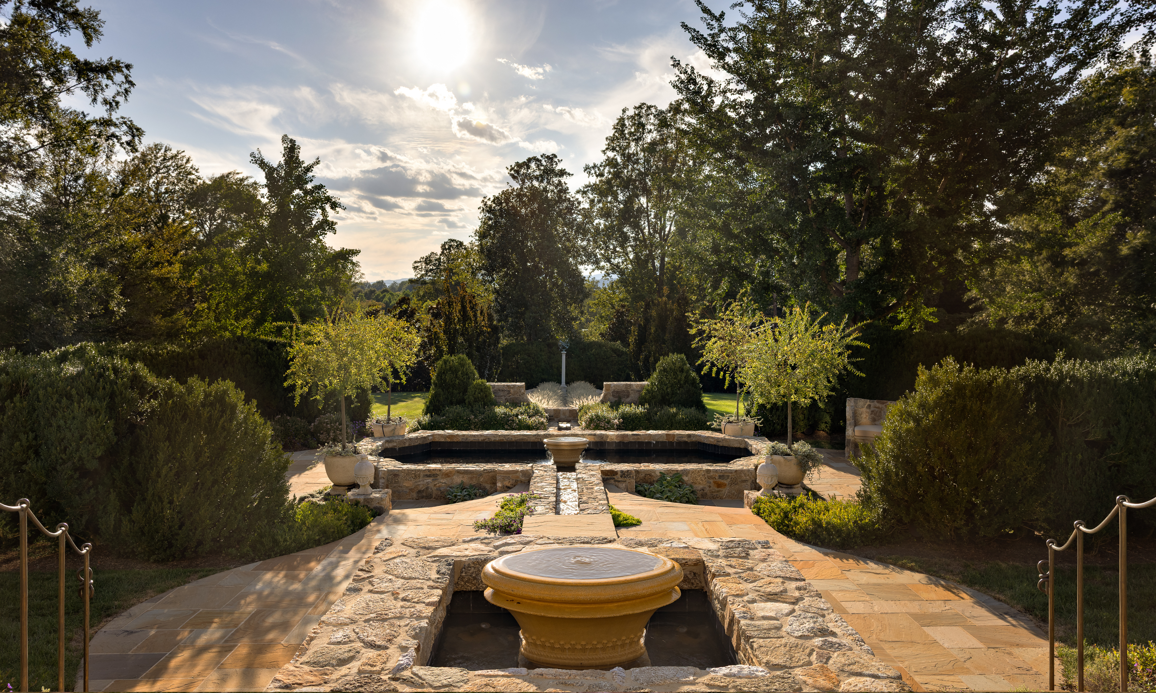 Stone rill and large water feature bordered by mature trees
