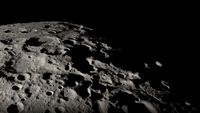 A close up of the moon's black and white, heavily cratered surface.