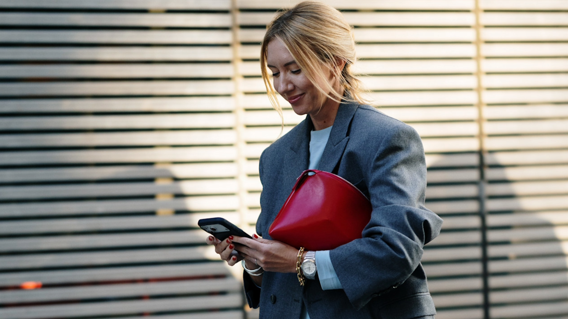 woman wearing a gray blazer and a white t -shirt and a red clutch