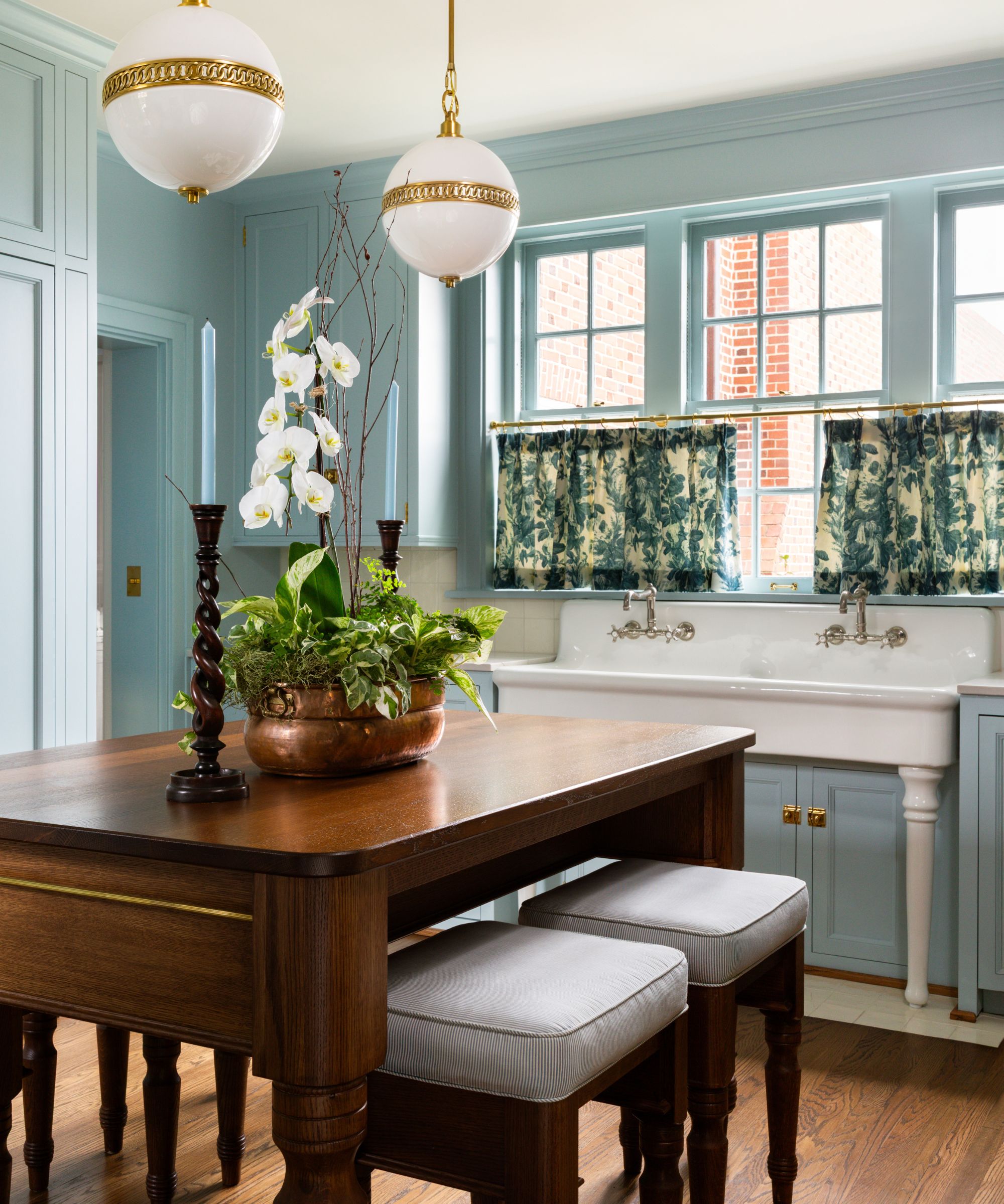 traditional kitchen with light blue walls and cabinets, wooden island unit and two bar stools