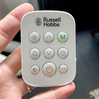 The Russell Hobbs RHPAC11001 Portable Air Conditioner remote control being held in a woman's hand