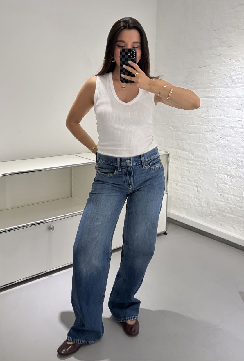 Woman wears white tank top, blue jeans and burgundy loafers