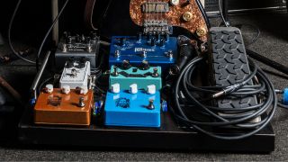 A pedalboard with a guitar cable on top of it