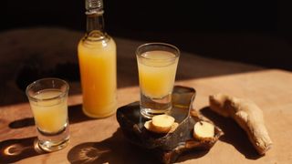 Ginger juice shots in glass poured from bottle