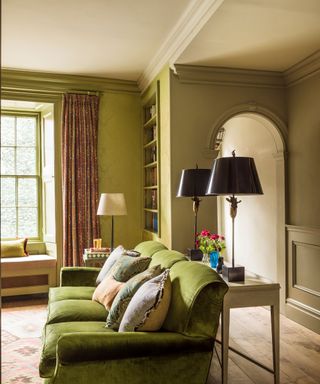 Traditional living room corner with green sofa and damask wallpaper, painted gray and white walls.