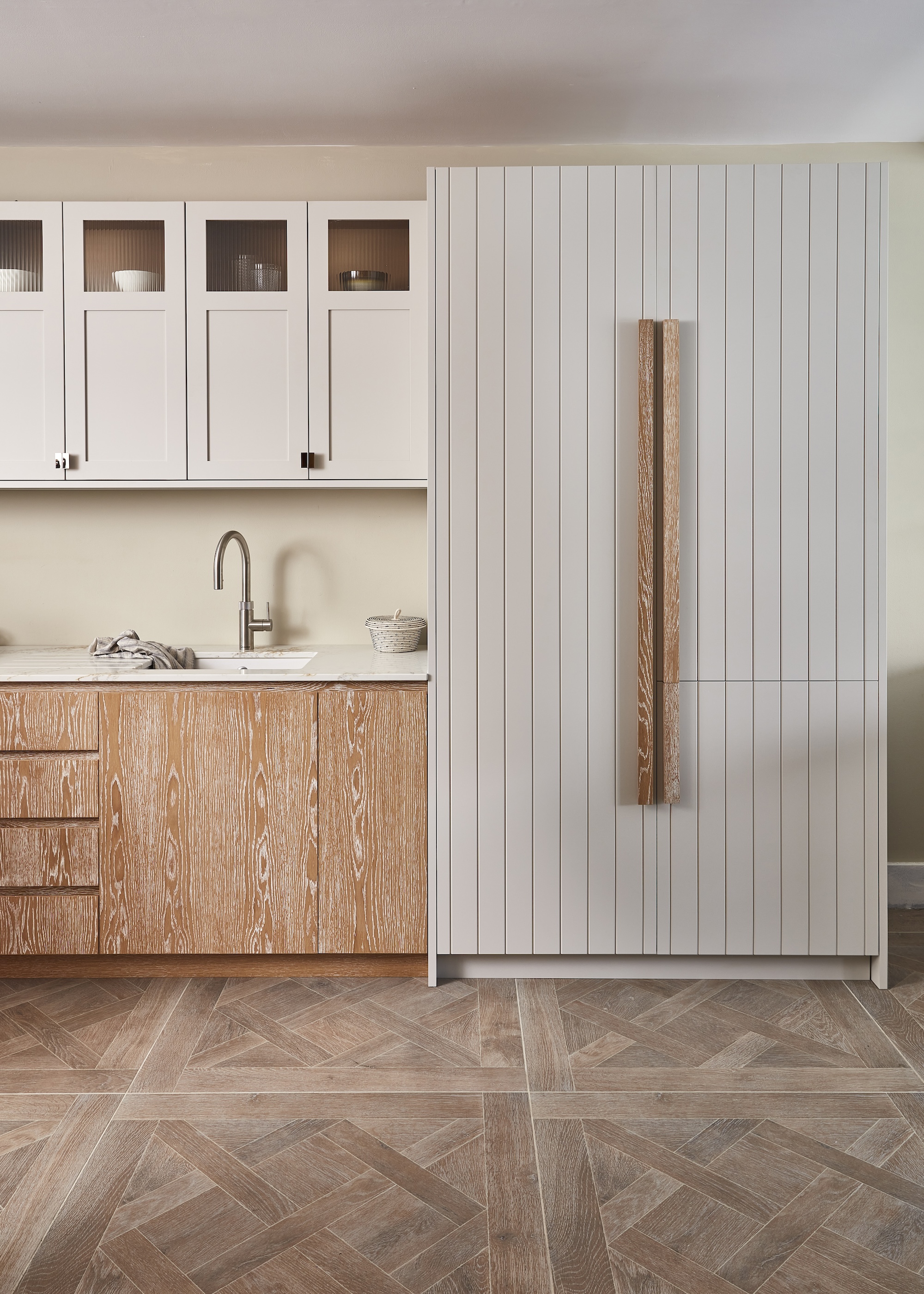 A Scandinavian style pale wood and white kitchen showing a mix of handles and handle-free cabinets