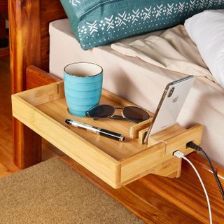 wooden bedside shelf with phone, mug and other accessories