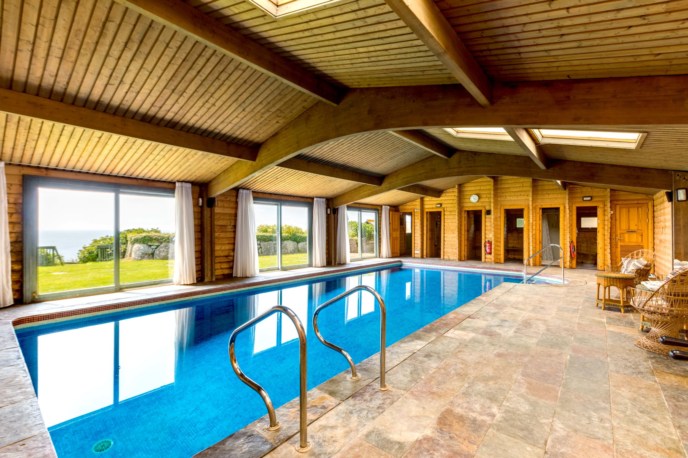 An indoor swimming pool with wooden timber structure and tiled flooring and changing rooms