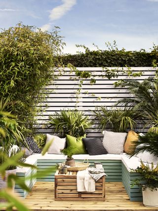 An outdoor space with colored deck and fence decor with outdoor seating area and outdoor cushion decor